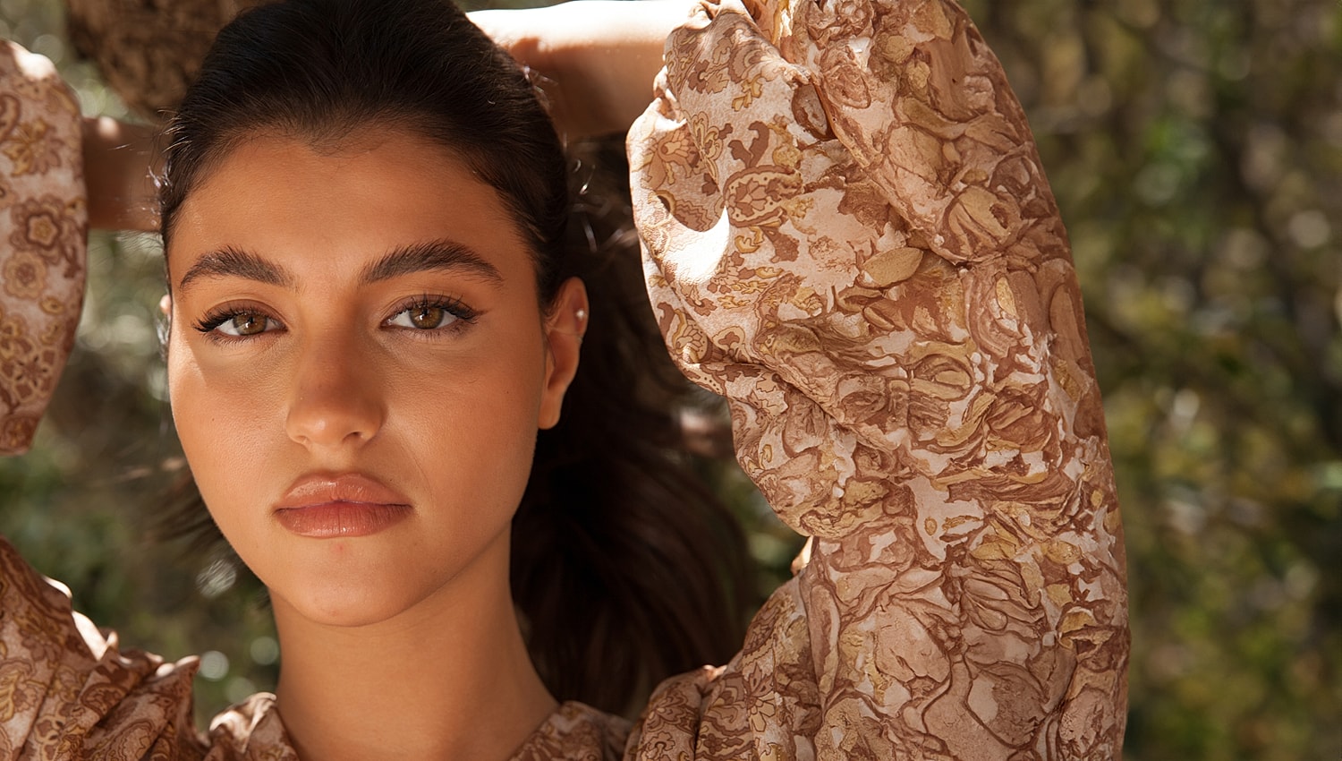 Young woman with brown eyes and floral blouse.