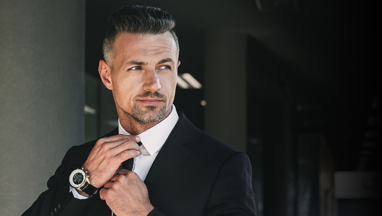 Man in a suit adjusting his collar